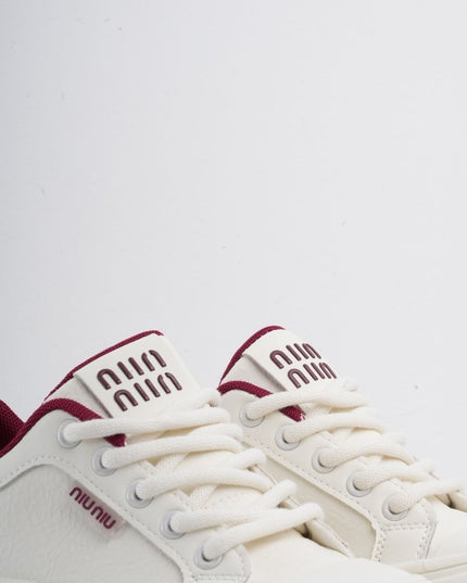 Tenis blancos con líneas y detalles vinotinto